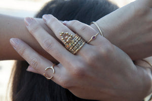Our Beatrix ring shown in 14 yellow gold and 7 round white diamonds shown stacked with other rings on hand