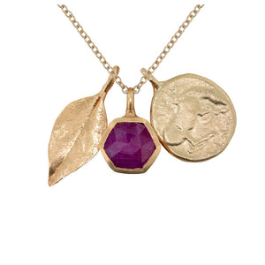 Yoko charm necklace this charm necklace features 3 charms a Ruby Hexagon for balance and love, a Leaf for happiness and our Horse Coin pendant signifying freedom in 14K yellow gold.