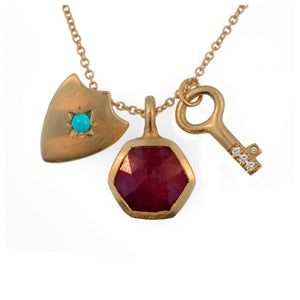 Our Allegra charm necklace features 3 charms a Ruby Hexagon for balance and love, a diamond key for affection and a Shield pendant with a turquoise center stone for protection.