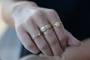 Our egg ring 14K yellow gold with round white diamond center stone and carved diamond shape shown on hand with other rings