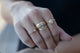 Our egg ring 14K yellow gold with round white diamond center stone and carved diamond shape shown on hand with other rings