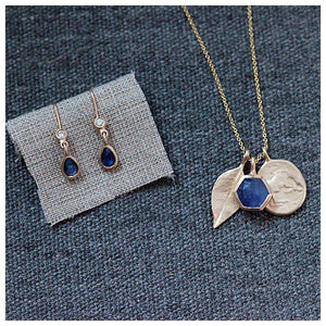 This charm necklace features 3 charms in 14K yellow gold with  a Blue sapphire Hexagon for balance and love, a Leaf for happiness and our Horse Coin pendant signifying freedom.