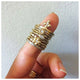 Our Anna ring in 14K yellow gold with 3 white round diamonds  shown stacked with other rings on finger