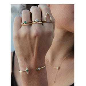 Our Beatrix ring shown in 14 yellow gold and 7 round white diamonds shown stacked with other rings on hand