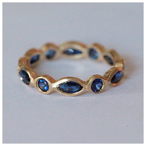Sapphire Eternity Ring with 6 marquis and 6 round blue sapphires all around in 14K yellow gold on gray background