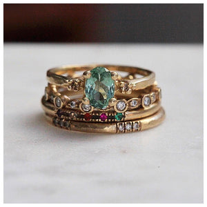 Our Candy ring with a green tourmaline center stone, 2 champagne diamond side stones shown in 14K Yellow gold. stacked with 3 bands.