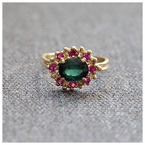 Simone ring with Green tourmaline oval center stone and 8 pink sapphires in 14K yellow gold on gray background
