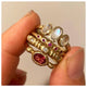 Odette ring in 14K Yellow gold with oval shaped Rubellite center stone shown stacked with other rings