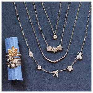 Our garden necklace shown in 14K gold with our blossom flower, bird, leaf, and laura flower shown with other necklaces