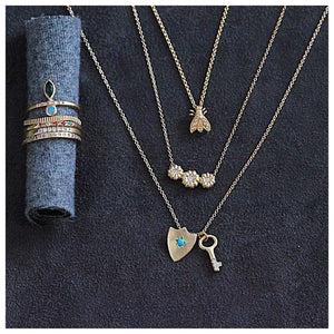 Bee necklace in 14K yellow gold with 3 white round diamonds in each wing  shown with other jewelry
