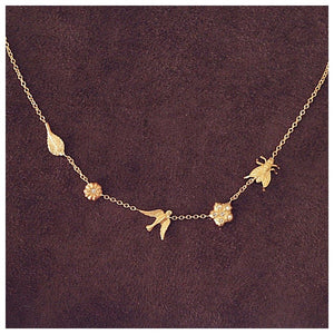 Our garden necklace shown in 14K gold with our blossom flower, bird, leaf, and laura flower