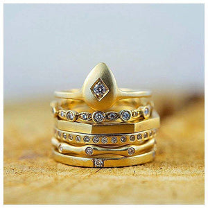 Our egg ring 14K yellow gold with round white diamond center stone and carved diamond shape shown stacked with other rings