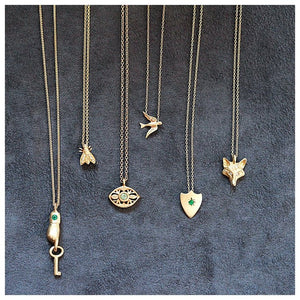 shield necklace is shown in 14K Yellow Gold with a green emerald center stone shown with other necklaces (Copy)