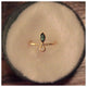Our Iris ring with a Green Tourmaline marquis, Opal round stone and Diamonds on the side shown in 14K yellow gold in a dish.
