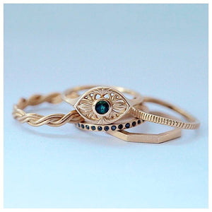 Luna ring in 14K yellow gold with round emerald center stone grouped with other rings