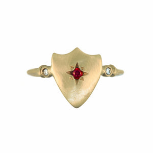 Shield ring shown in 14K yellow gold with ruby round center stone and 2 white diamonds on side