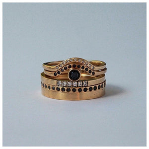 Sunrise Center ring in 14K yellow gold with round black  diamond center stone and 11 black diamonds in arch  shown stacked with other rings